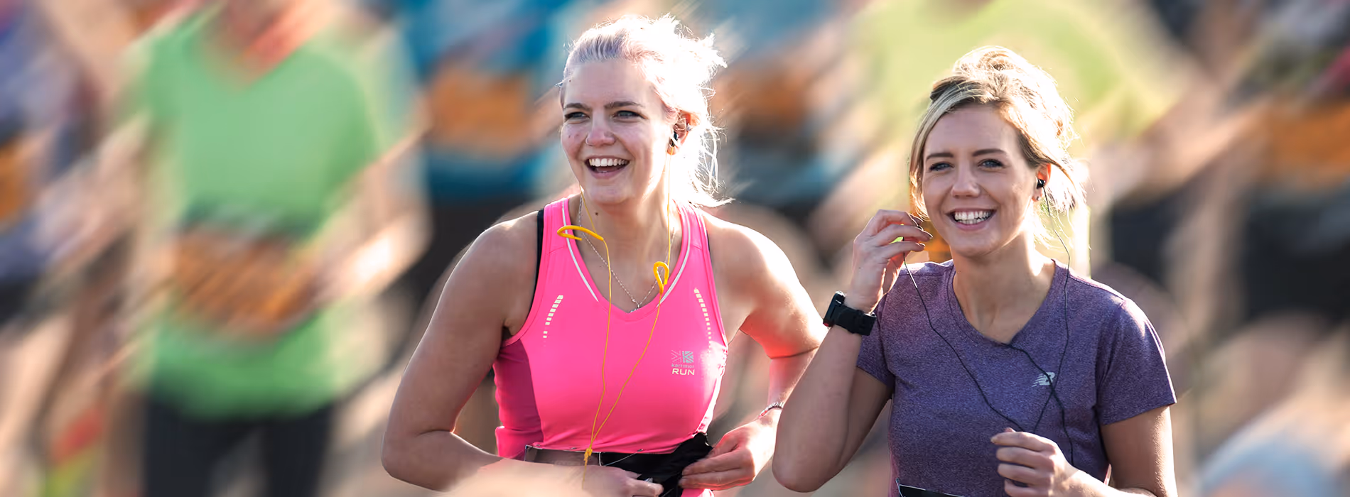 Image shows a smiling runner celebrating with arms in the air at the finish line