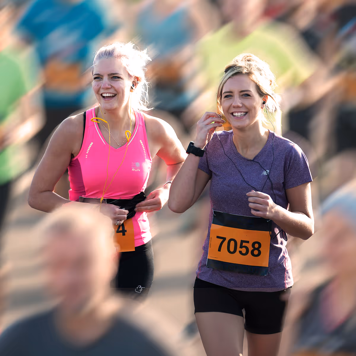 Image shows a smiling runner celebrating with arms in the air at the finish line