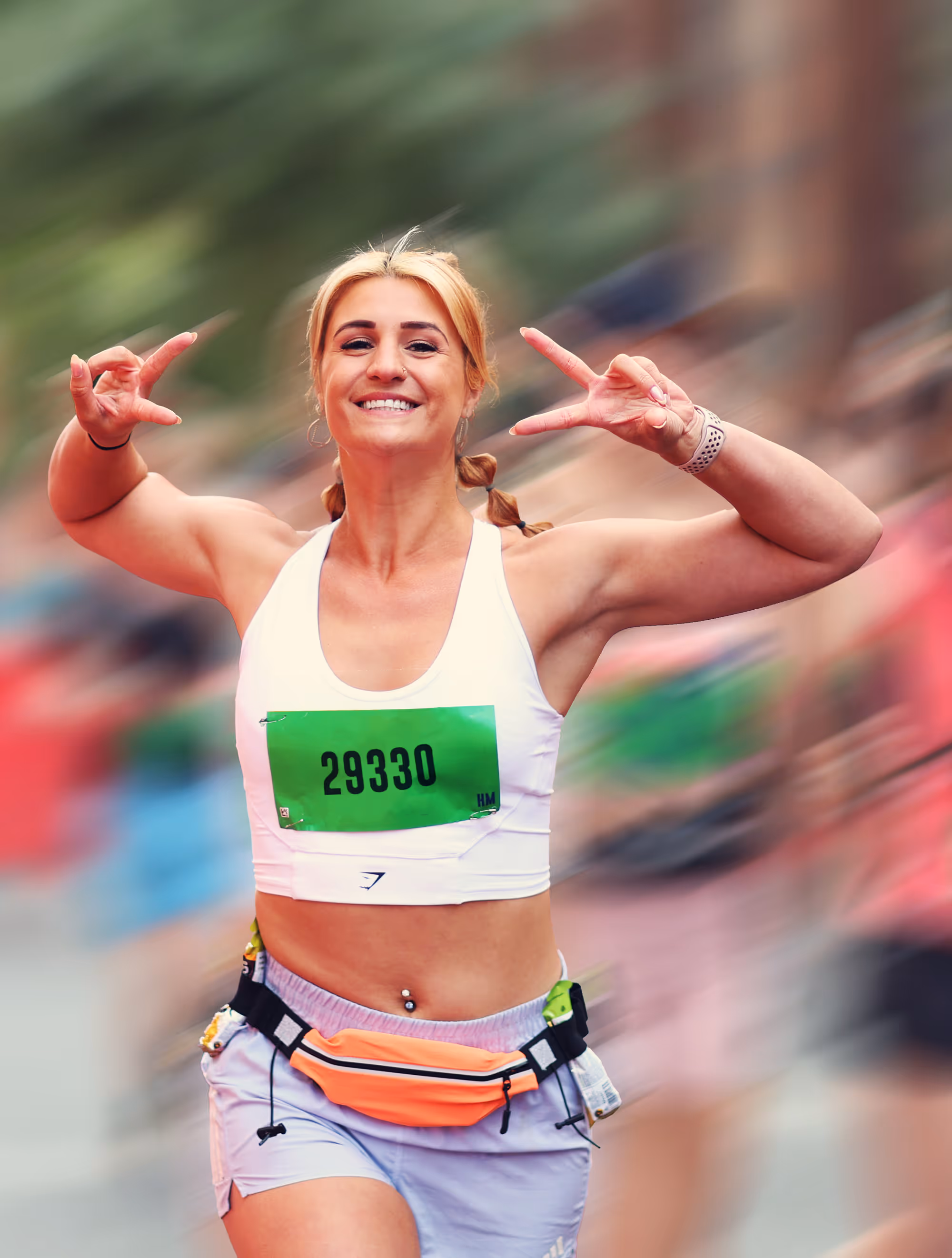 Image shows a female runner approaching the finish line with arms stretched in the air