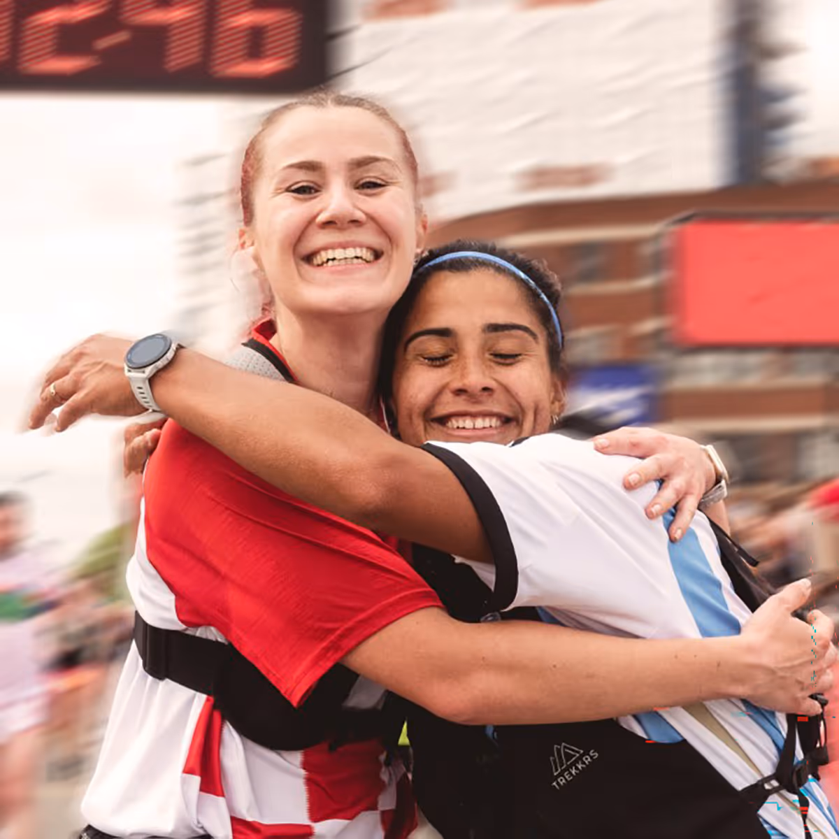 Image shows two happy smiling runners embracing on the finish line