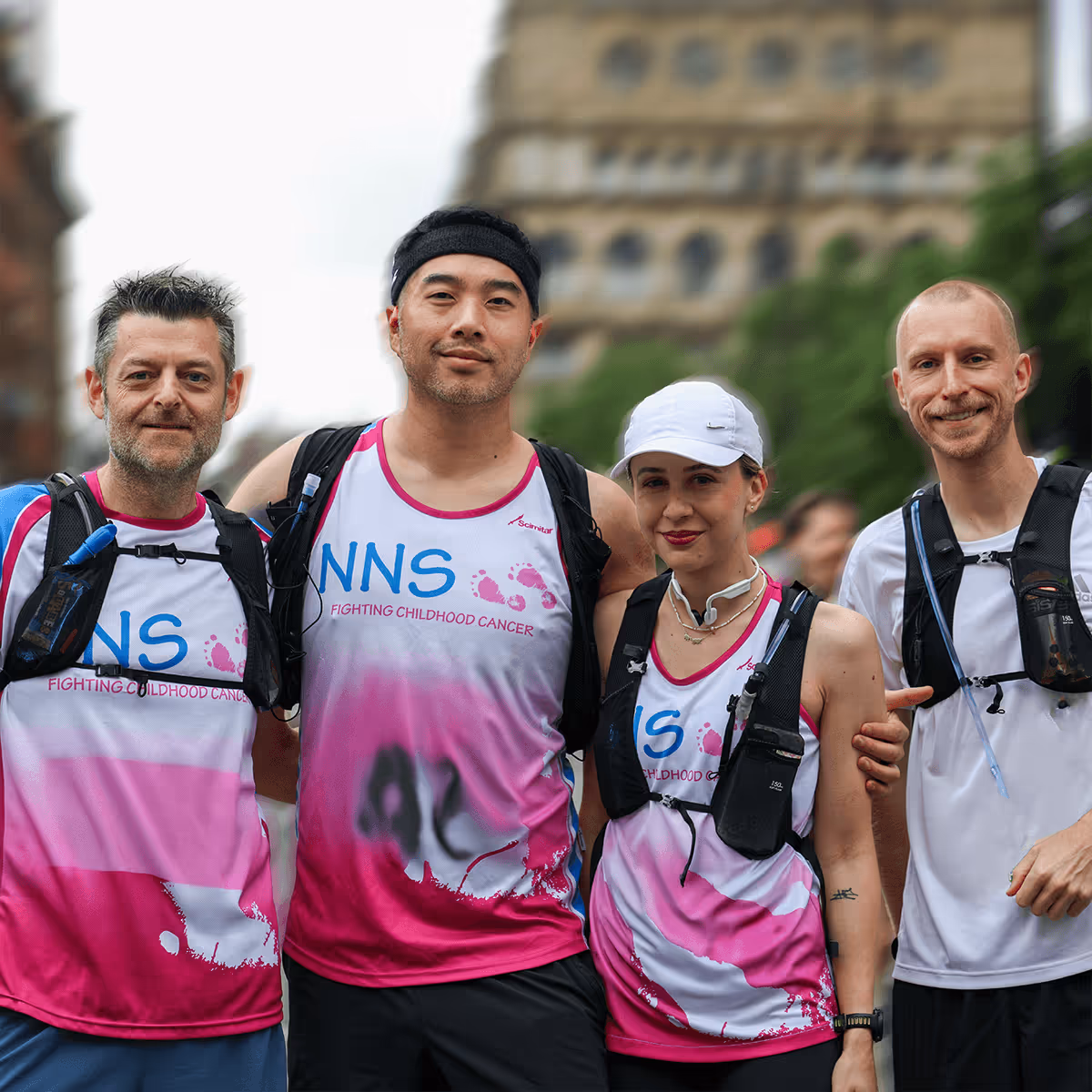 Image shows a group of four runners in charity t-shirts smiling at the camera