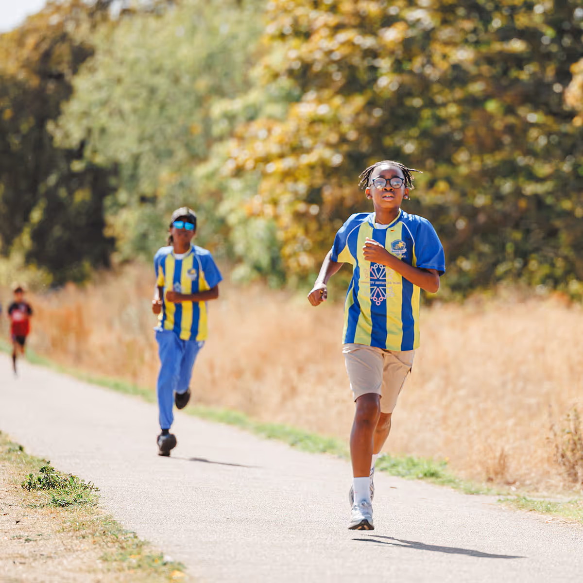 Image shows smiling school children running in a race through a park in South London